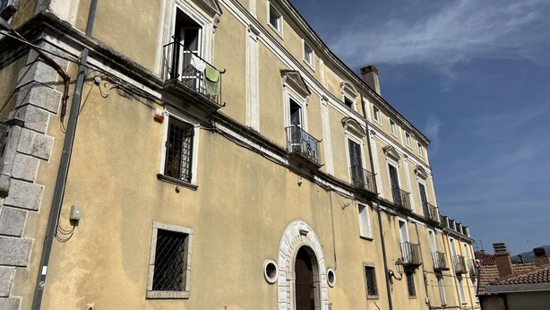 A multi-story building with arched windows and balconies, a visible door, and a clear sky. - Vintage Holiday Home in Caselle in Pittari near Forest (Caselle in Pittari)