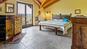 Ein Schlafzimmer mit einem großen Bett, Holzbalkendecke, einem Schminktisch und Blick durch eine Schiebetür.