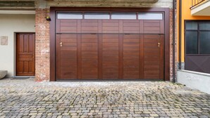 Eine große Holztür zu einer Garage, mit einer Ziegelwand und einem Betonüberhang.