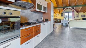 Eine geräumige Küche mit modernen Geräten, Holzschränken und einer hohen Decke mit sichtbaren Balken.