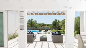 A modern outdoor patio with a pool, furnished with sofas and chairs, and framed pictures on the wall. - Villa in Debeljak With Pool Near the Sea (Sukosan)