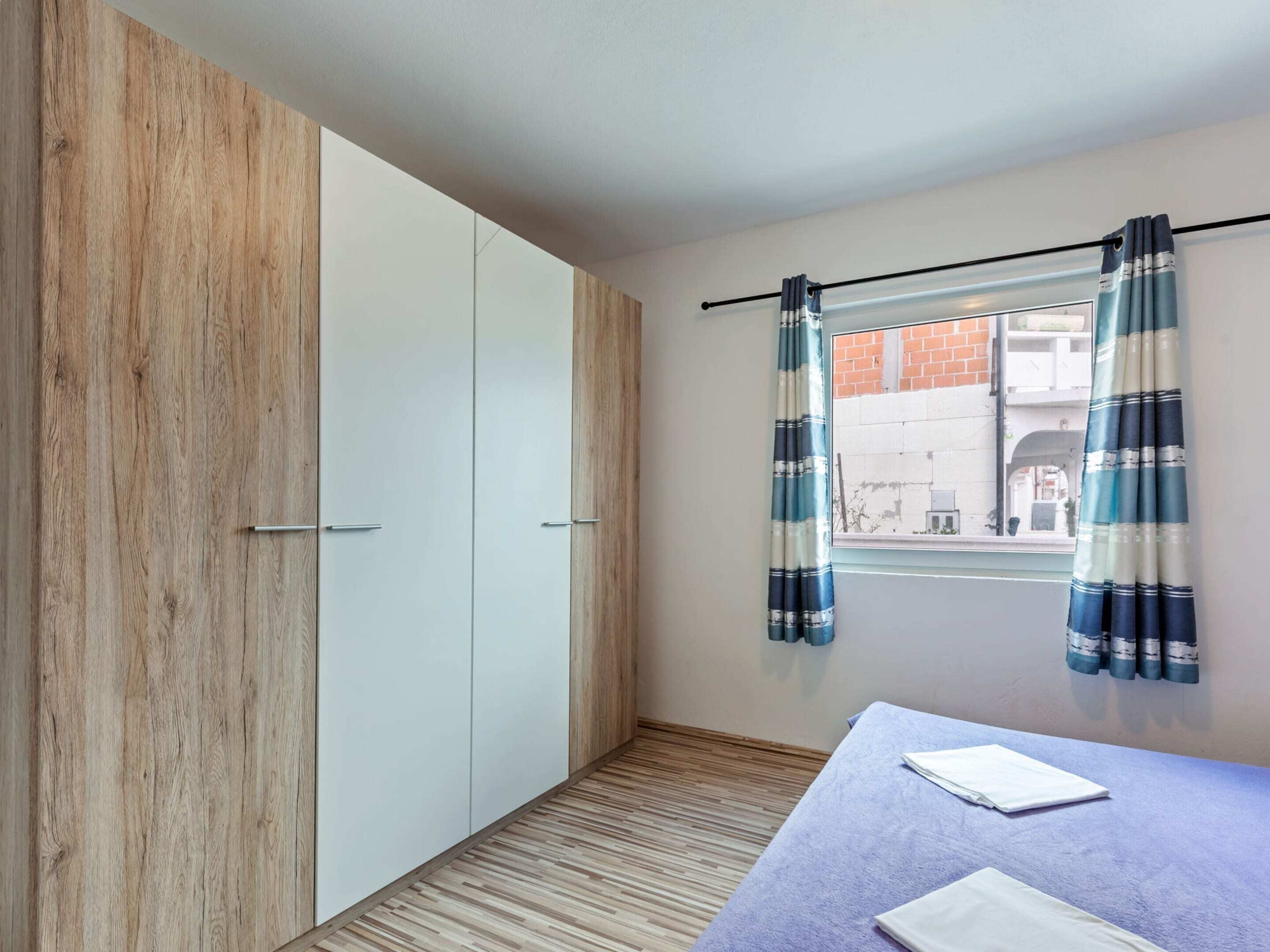 Una habitación con armario, cama y ventana con cortinas.