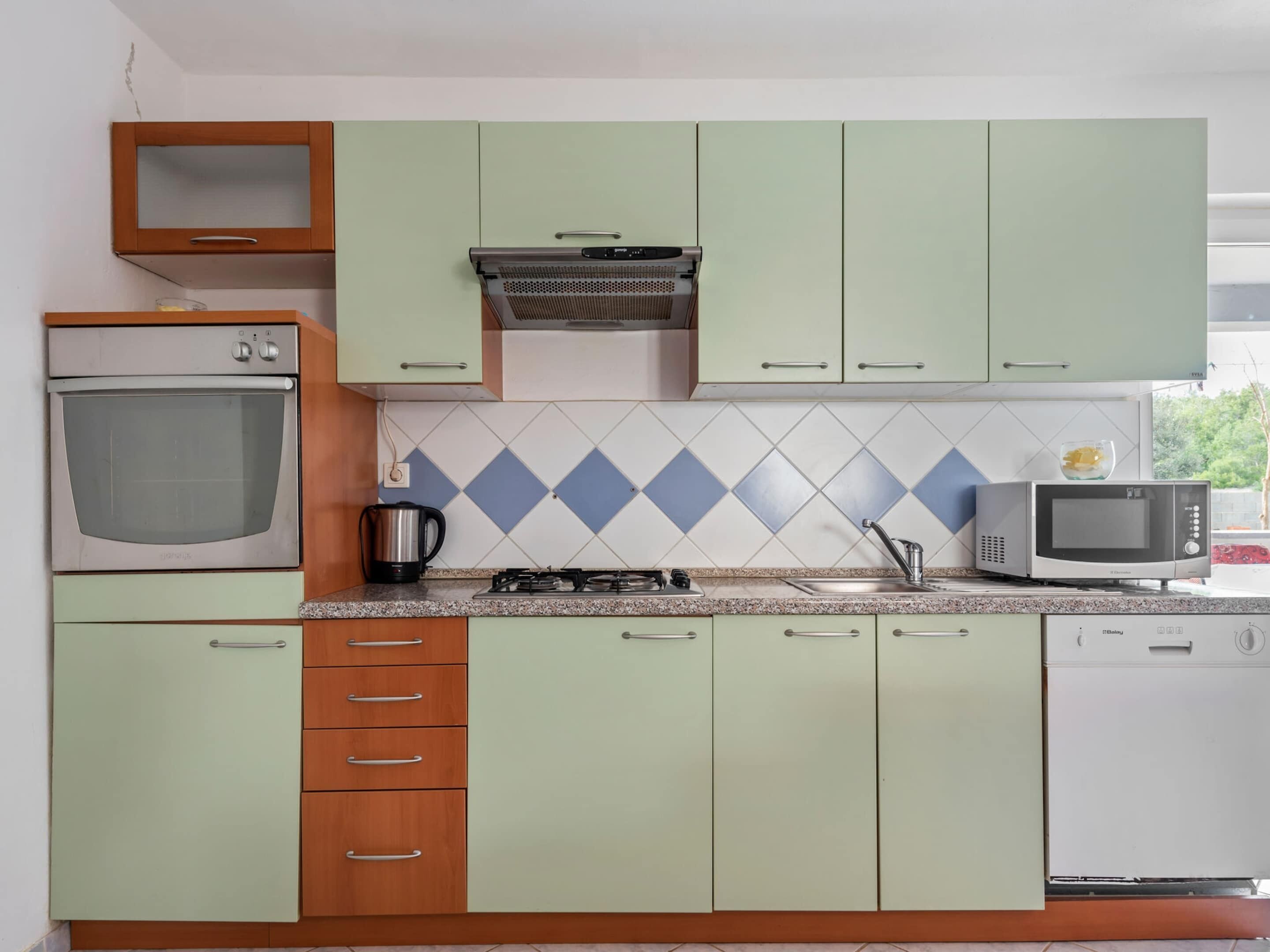 A kitchen with a stove, oven, microwave, and cabinets.