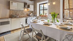 Eine moderne Küche mit weißen Schränken, einer Holzbalkendecke und einem Essbereich, der für eine Mahlzeit gedeckt ist.