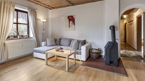 Ein gemütliches Wohnzimmer mit Sofa, Tisch, Kamin und einem Fenster mit Vorhängen.