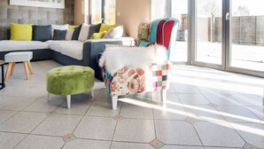 A modern living room with a sectional sofa, a green ottoman, and a colorful armchair. - Luxurious Villa in Durbuy With Swimming Pool (Durbuy)