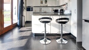 A modern kitchen with two bar stools, a built-in oven, and a large window. - Luxurious Villa in Durbuy With Swimming Pool (Durbuy)
