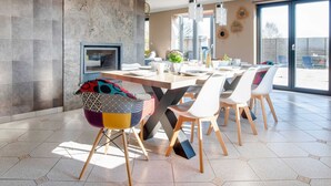 A modern dining area with a large table, chairs, and a television on a wall. - Luxurious Villa in Durbuy With Swimming Pool (Durbuy)