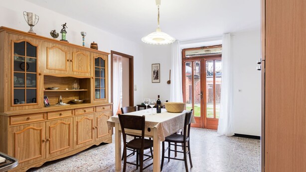 Un coin repas comprenant un buffet en bois, une table avec des chaises et un sol carrelé.