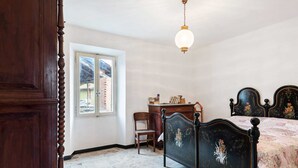 Une chambre à coucher avec un lit, un bureau et une chaise. Il y a une fenêtre qui donne sur les bâtiments à l’extérieur.