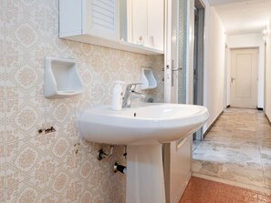 A bathroom with a white sink, patterned tiles, and a door leading to another room. - Belvilla by OYO Casa Rina (Predosa)
