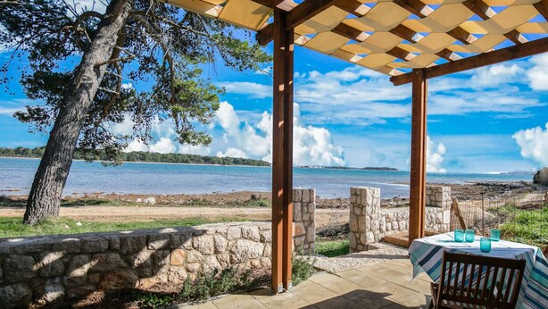 A covered outdoor seating area with a view of a lake and distant land. - Secluded Holiday Home in Pašman near Sea (Pasman)