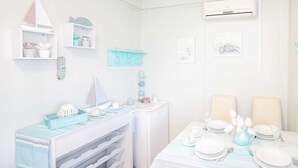 A dining area with a table set for two, a small refrigerator, and a wall-mounted air conditioner. - Secluded Holiday Home in Pašman near Sea (Pasman)