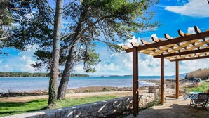 A covered outdoor seating area with stone walls and a view of the sea. - Secluded Holiday Home in Pašman near Sea (Pasman)