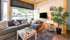 A modern living room with a sectional sofa, a coffee table, a lamp, and a potted plant. - Holiday Home in Meijel Near De Groot Peel Park (Meijel)