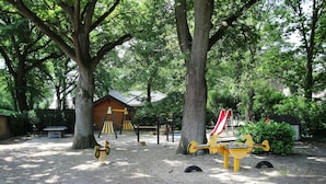 A playground with swings, a slide, and a seesaw. - Holiday Home in Meijel Near De Groot Peel Park (Meijel)