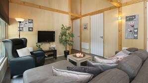 A cozy living room with a leather sofa, a wooden coffee table, a potted plant, and a flat-screen TV. - Holiday Home in Meijel Near De Groot Peel Park (Meijel)