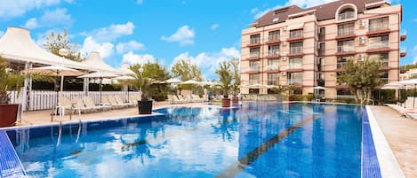 Una piscina al aire libre de temporada, sombrillas, tumbonas