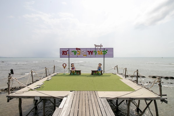 A wooden pier with a green platform and two children playing.