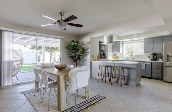Enjoy meals in the spacious kitchen and dining area, featuring a large island, bar stools, and a wooden table with comfortable seating.