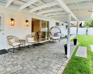 Relax in style on the patio, surrounded by lush greenery and a charming pergola.