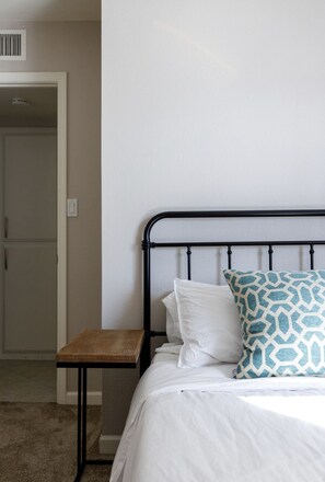 Simple, clean room with a single bed, nightstand, and minimalist design.