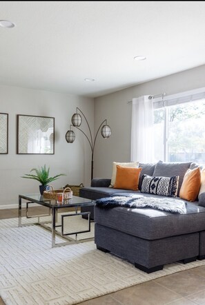 Relax in this stylish living room with a sofa, coffee table, and floor lamp, surrounded by artwork and a potted plant.
