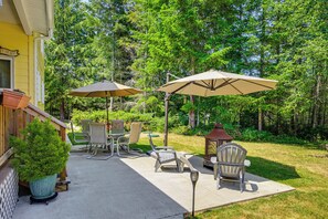 An outdoor patio with a table and chairs, two umbrellas, and a small lamp. - Hot Tub, Deck + Game Room: Port Angeles Home (Port Angeles)
