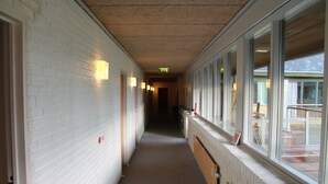 A corridor with white brick walls, a wooden bench, and a window with a view of the outside. - Danhostel Sakskøbing (Sakskobing)
