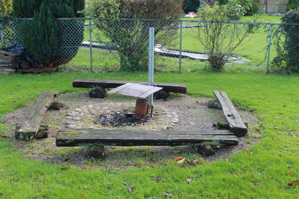 A garden with a wooden bench, a metal table, and a metal pole. - Danhostel Sakskøbing (Sakskobing)