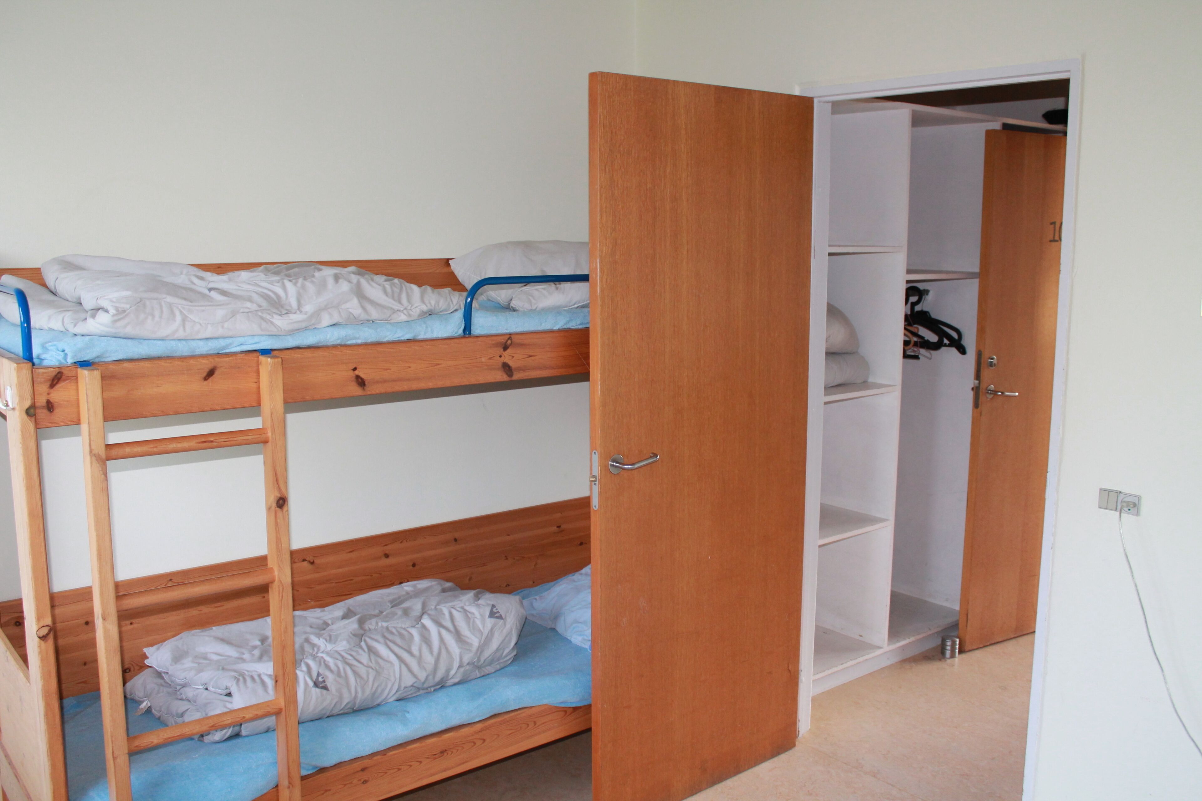 A bunk bed room with a wooden door leading to a closet.