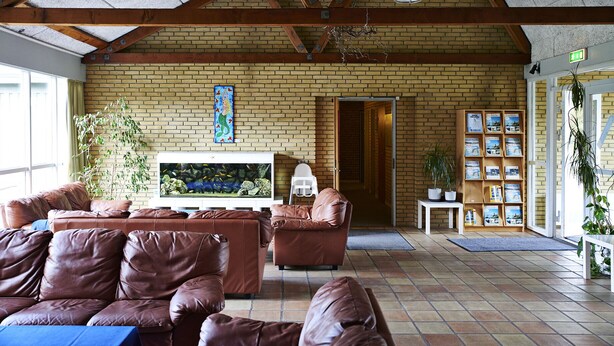 A spacious lobby with leather sofas, a large aquarium, and a brick wall. - Danhostel Sakskøbing (Sakskobing)