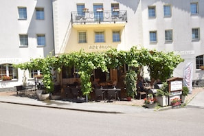 A restaurant with outdoor seating, covered by vines, and a sign reading "ARKANUM". - Hotel Arkanum (Salgesch)