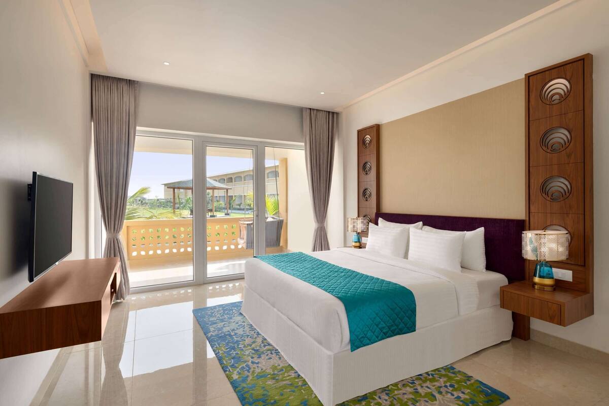 Una habitación de hotel con cama, televisión, escritorio y vista al exterior.