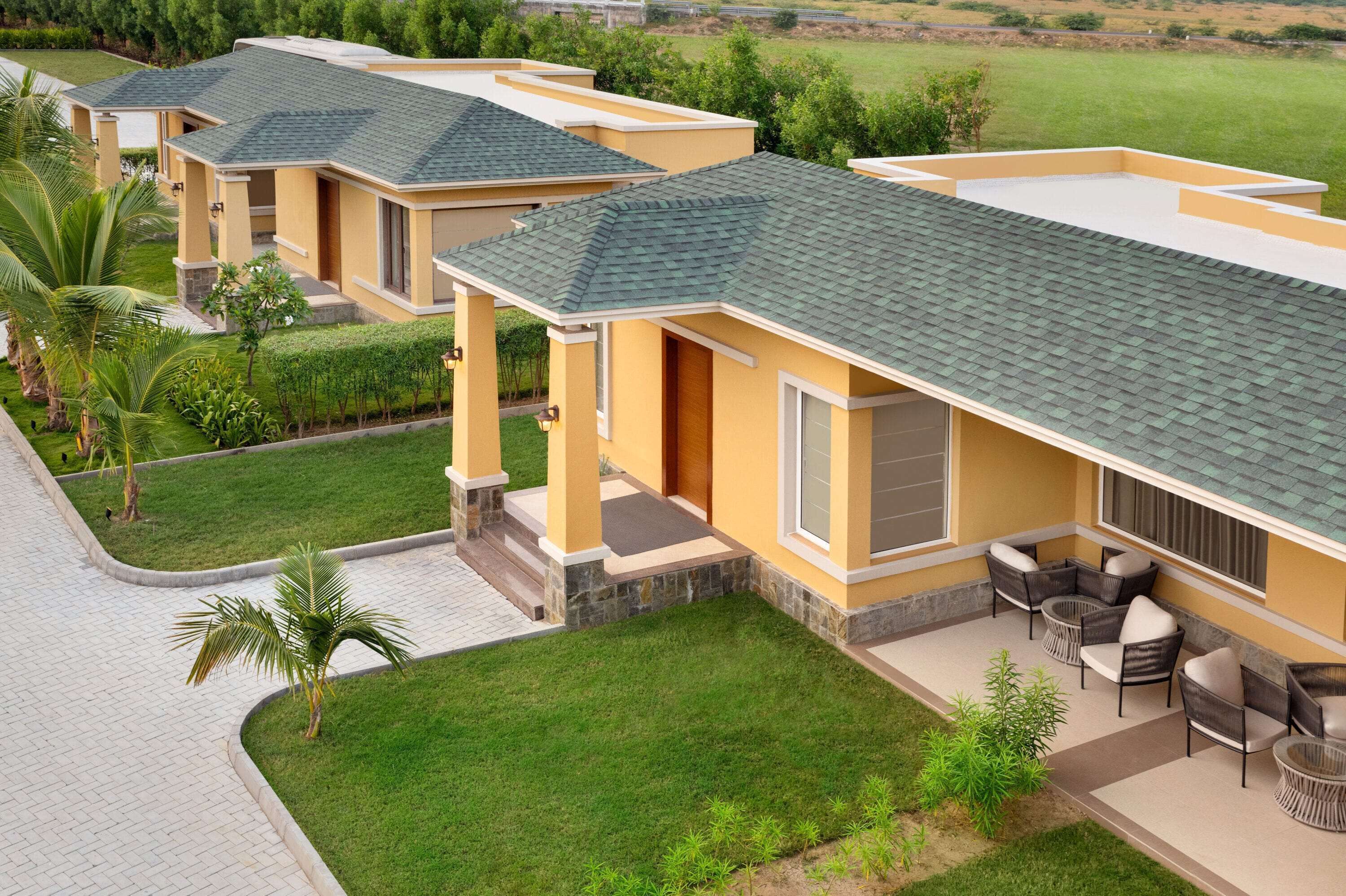 A residential building with a flat roof, a patio with outdoor furniture, and a well-maintained lawn.