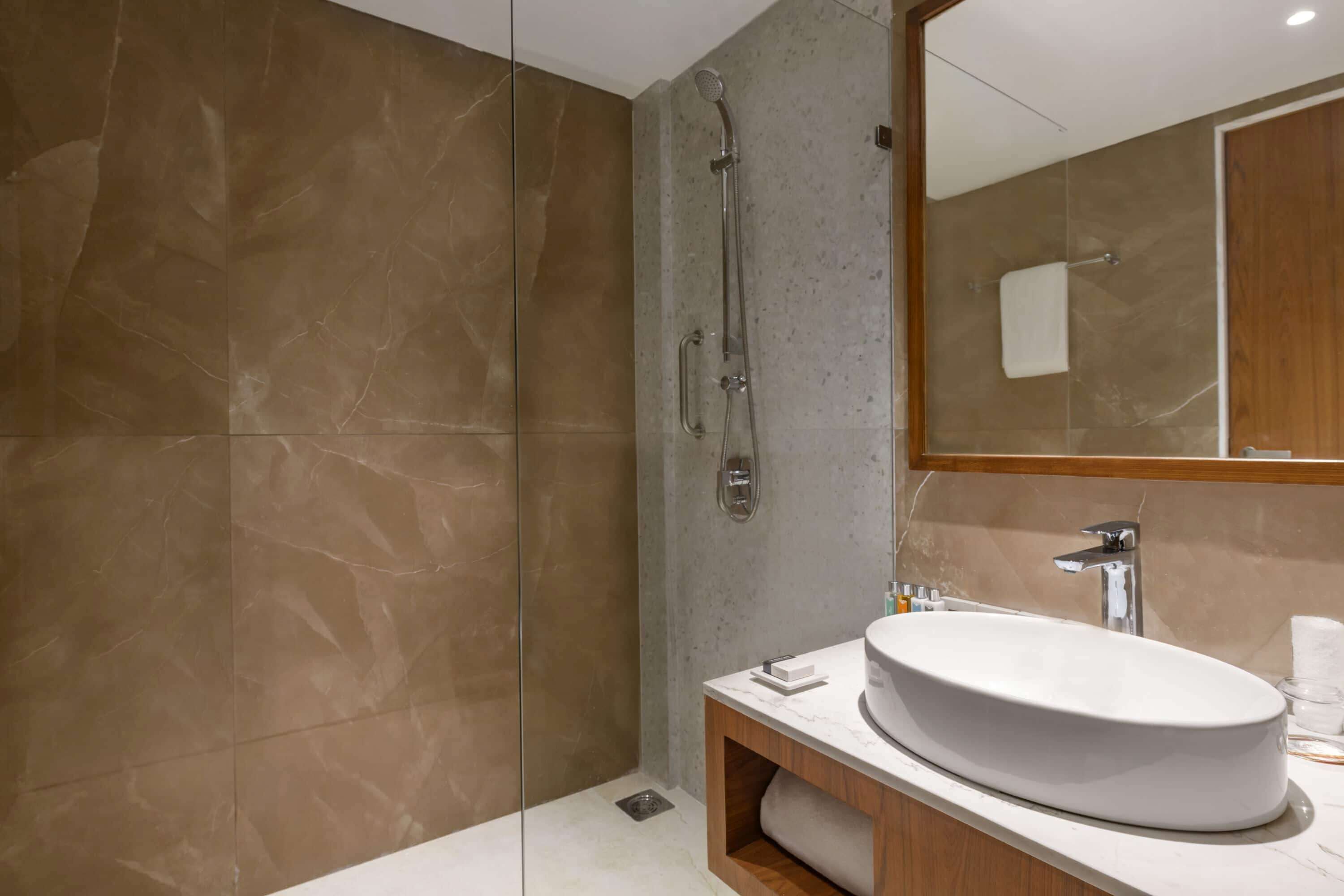 A modern bathroom with a large oval sink, a glass-enclosed shower, and a wooden vanity.