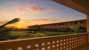 Un hotel con un área exterior techada, una piscina y un edificio con varios balcones.
