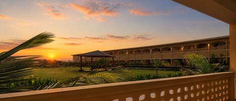 A hotel with a covered outdoor area, a pool, and a building with multiple balconies.