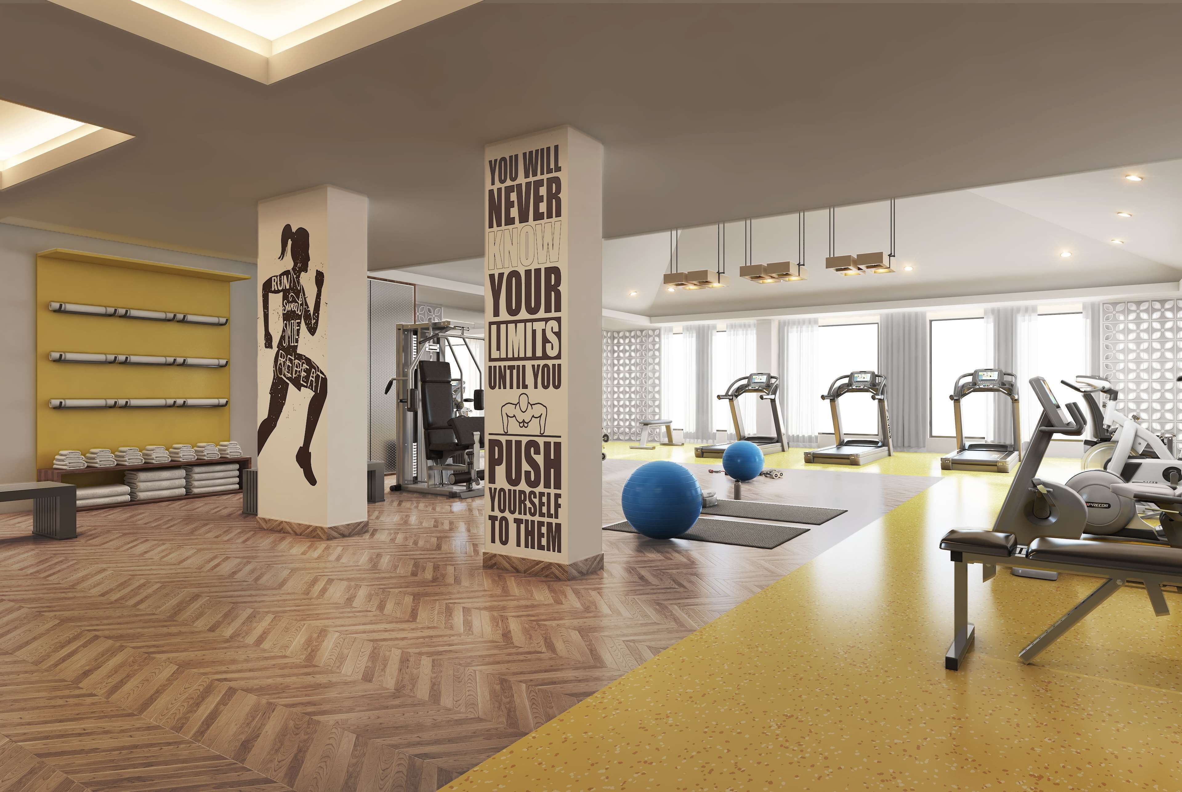 A modern gym with exercise equipment, motivational wall art, and a wooden floor.