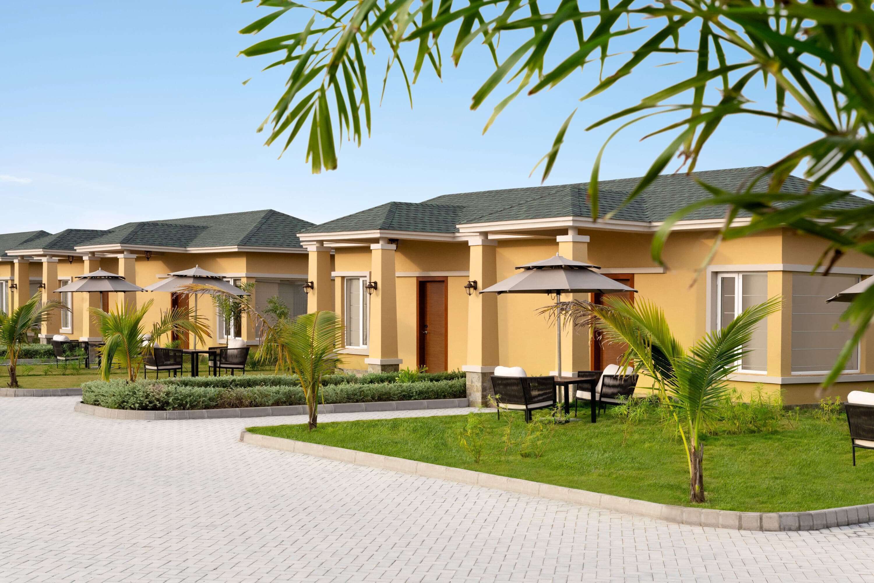Una hilera de habitaciones de hotel modernas con zonas de estar al aire libre y palmeras.