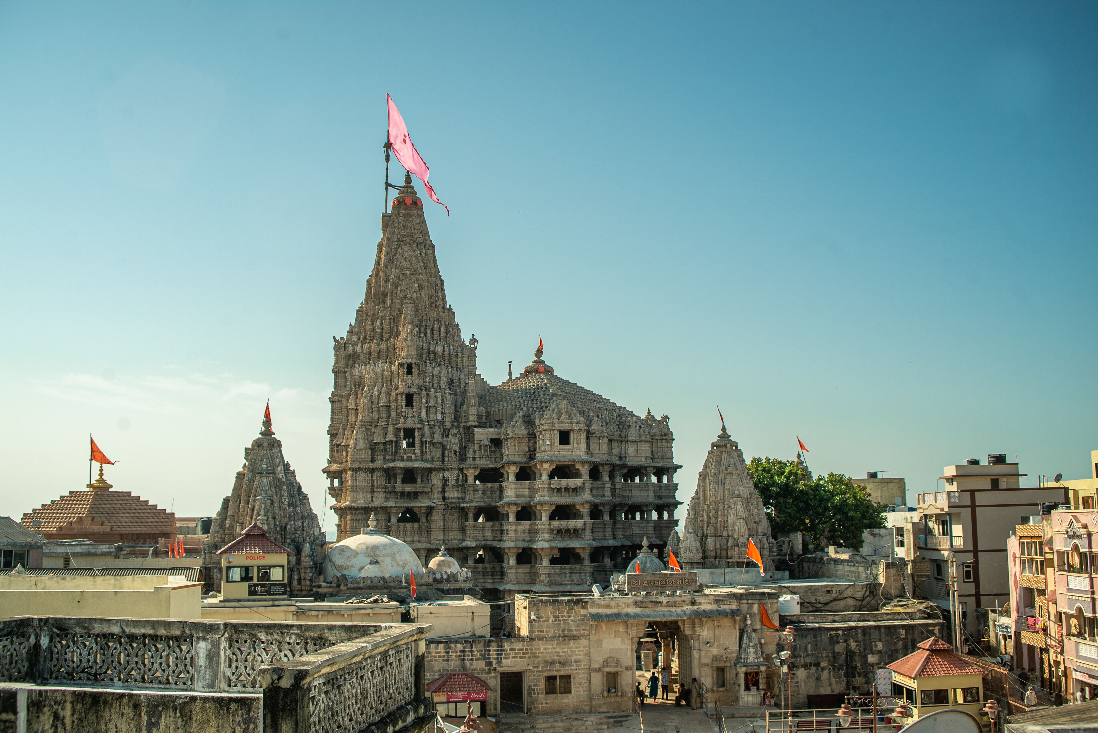 A large, multi-tiered temple complex with multiple spires and flags, surrounded by modern buildings.