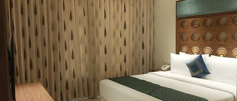 A hotel room with a bed, a nightstand, a telephone, and a wall with a decorative panel.