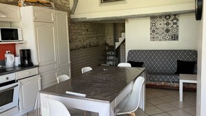 A compact kitchen with a dining table, chairs, a microwave, a coffee maker, and a patterned sofa. - Charming House with Terrace & Garden, Near La Roche-Posay Town Center (La Roche-Posay)