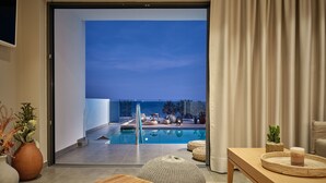 A modern living room with a glass door leading to a pool area. - Oceanis Luxury Suites (Zakynthos)