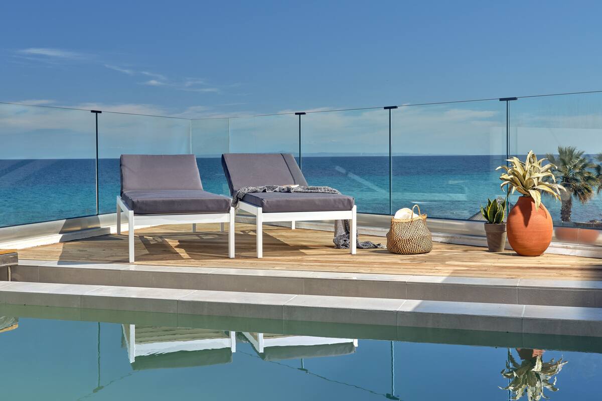 Zona de piscina con dos sillas de descanso, una planta en maceta y una cesta de mimbre.
