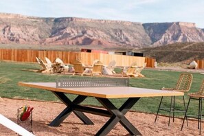 An outdoor table tennis table with chairs, a wooden fence, and a mountainous landscape in the background. - Zion Wildflower Resort, WorldHotels Backdrop (Virgin)