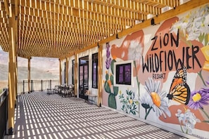 A covered outdoor area with a mural of flowers and a butterfly, a table, and chairs. - Zion Wildflower, BW Premier Collection (Virgin)