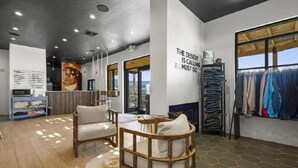 A modern interior with a sofa, a wooden chair, a clothing rack, and a wall with a motivational quote. - Zion Wildflower Resort, WorldHotels Backdrop (Virgin)