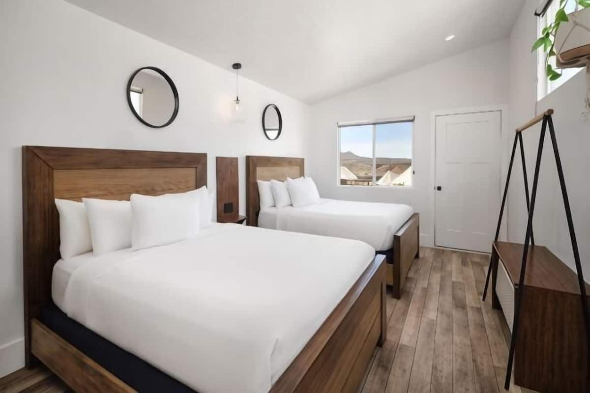 A hotel room with two beds, a large window, and a view of the mountains.