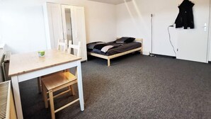 A small, sparsely furnished room with a single bed, a desk, and a chair. - Apartment Hainstädter Straße (Hanau)